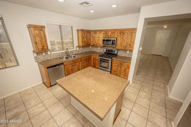 40808 N Raleigh Ct, Anthem, AZ 85086 - kitchen with appliances with stainless steel finishes, a sink, tasteful backsplash, light tile patterned flooring, and brown cabinets