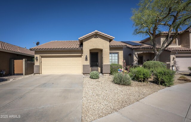 40808 N Raleigh Ct, Anthem, AZ 85086 - mediterranean / spanish home with stucco siding, a tiled roof, an attached garage, concrete driveway, and roof mounted solar panels