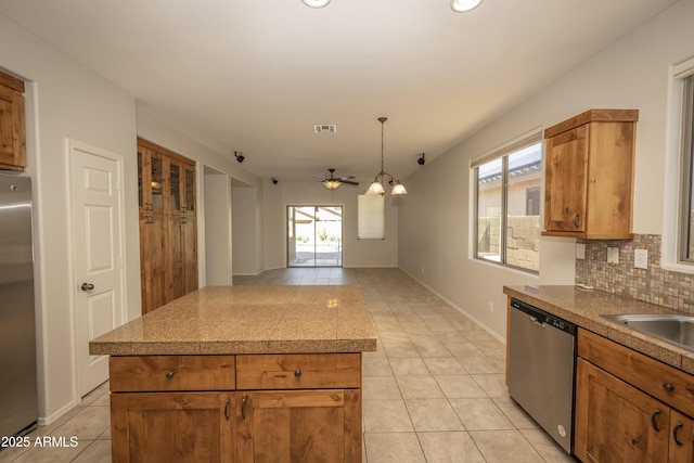 40808 N Raleigh Ct, Anthem, AZ 85086 - kitchen featuring stainless steel appliances, light tile patterned floors, a ceiling fan, decorative backsplash, and brown cabinets