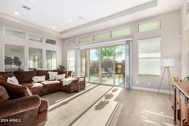 living room featuring a raised ceiling and light hardwood / wood-style flooring