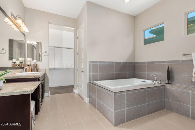 bathroom featuring tile patterned flooring, vanity, and tiled tub