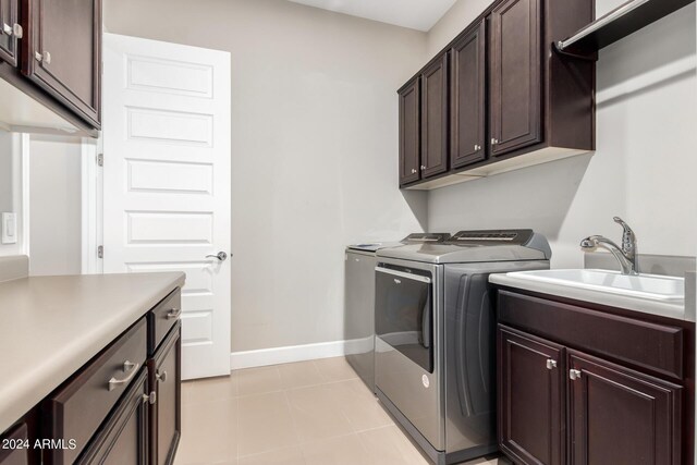 clothes washing area featuring light tile patterned floors, washing machine and clothes dryer, cabinets, and sink