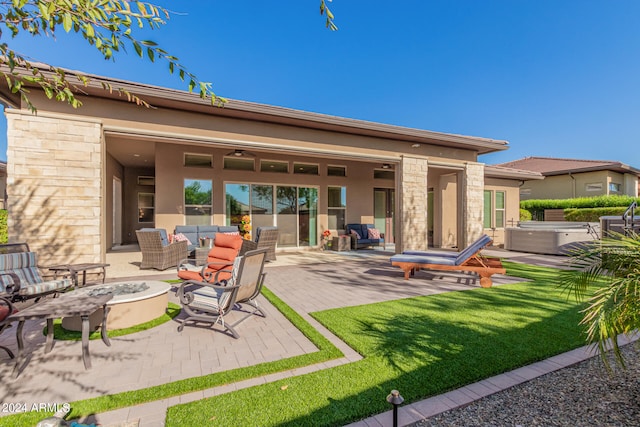 back of house with a fire pit, a hot tub, a yard, and a patio