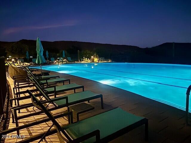 pool at night with a mountain view and a patio