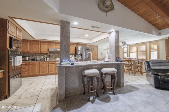 1285 E Mcmurray Blvd, Casa Grande, AZ 85122 - kitchen featuring stainless steel appliances, a tray ceiling, under cabinet range hood, a breakfast bar, and lofted ceiling