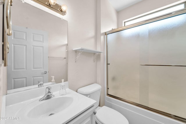 full bathroom with combined bath / shower with glass door, vanity, and toilet