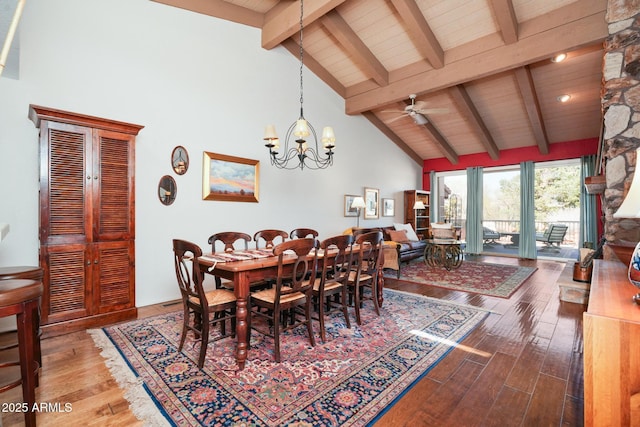 dining space with ceiling fan with notable chandelier, high vaulted ceiling, wood finished floors, and beam ceiling