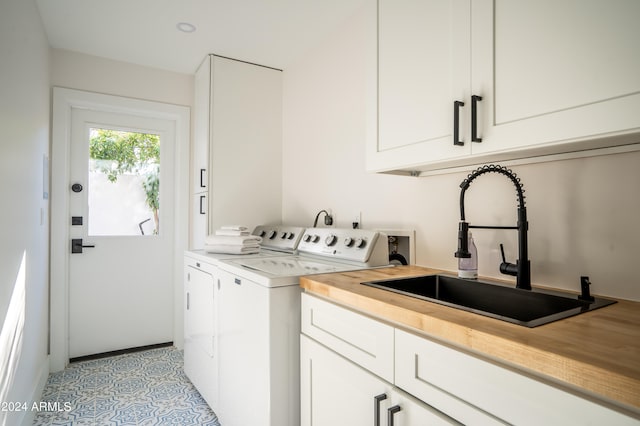 clothes washing area with sink, washing machine and dryer, light tile patterned flooring, and cabinets