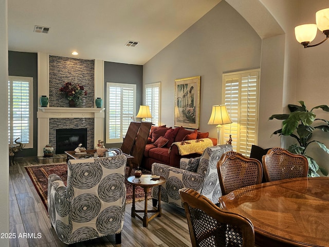 living room with lofted ceiling, a fireplace, and an inviting chandelier