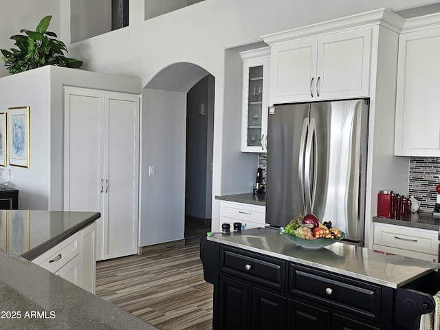 kitchen with backsplash, stainless steel refrigerator, white cabinets, and dark hardwood / wood-style floors