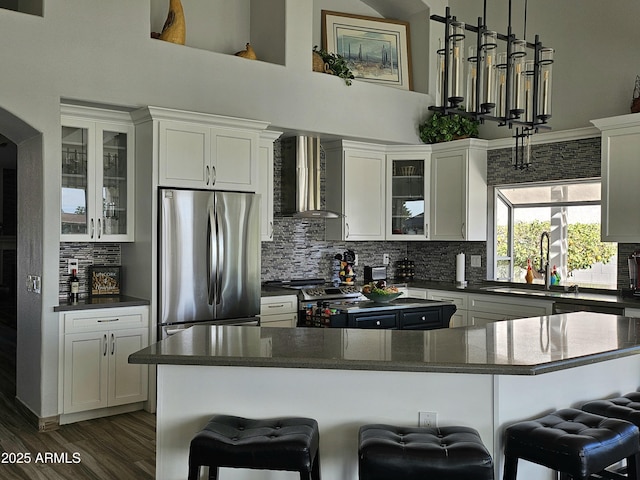 kitchen with a breakfast bar, wall chimney exhaust hood, and appliances with stainless steel finishes