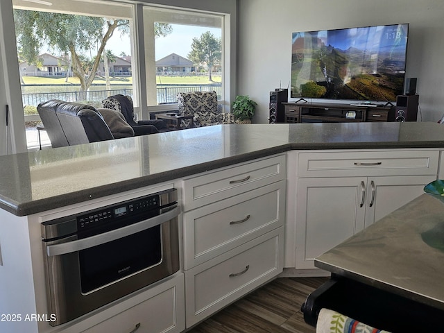 kitchen featuring dark hardwood / wood-style flooring, oven, and white cabinetry