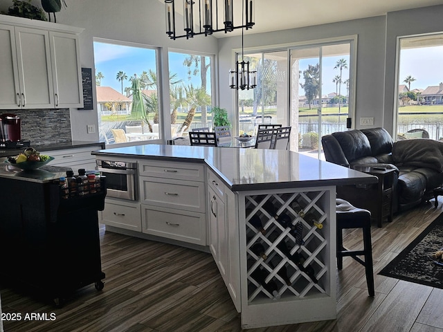 kitchen with white cabinets, pendant lighting, a water view, and tasteful backsplash