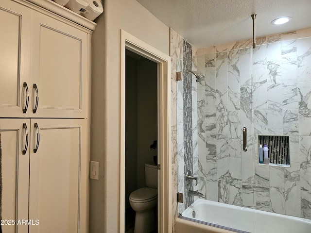 bathroom featuring toilet, bath / shower combo with glass door, and a textured ceiling