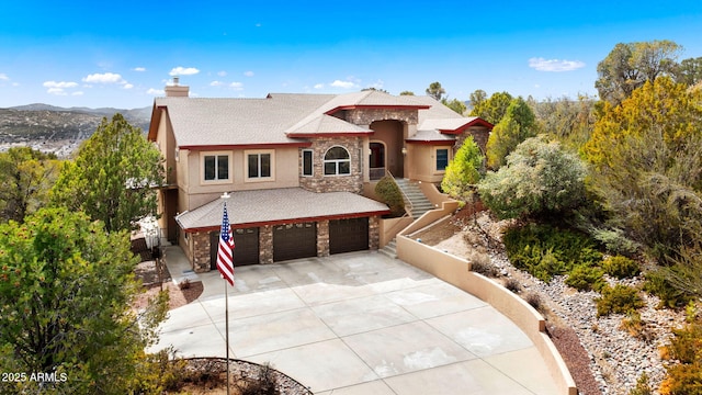 view of front of house featuring stucco siding, stone siding, concrete driveway, an attached garage, and a chimney