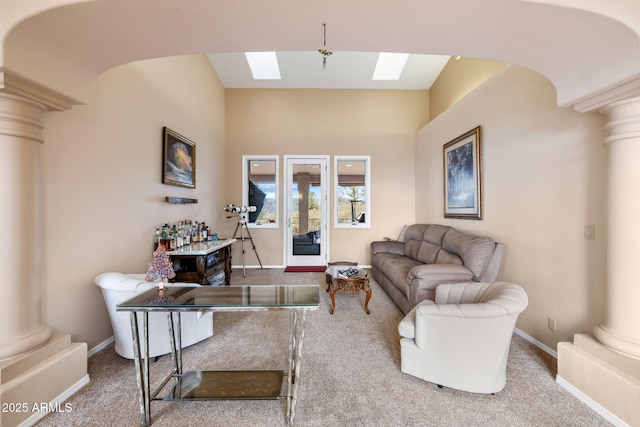 carpeted living area featuring a skylight, baseboards, and ornate columns