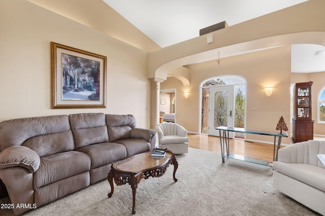 living area with baseboards, arched walkways, wood finished floors, and vaulted ceiling