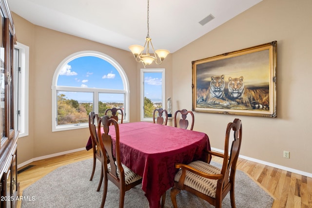 dining space with light wood-type flooring, visible vents, an inviting chandelier, baseboards, and vaulted ceiling