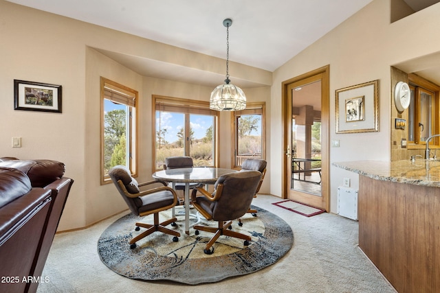 dining room featuring a wealth of natural light, indoor wet bar, light colored carpet, and vaulted ceiling