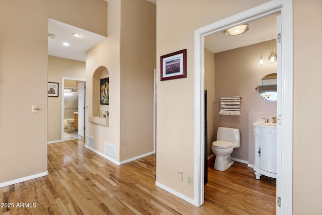 bathroom with toilet, vanity, baseboards, and wood finished floors