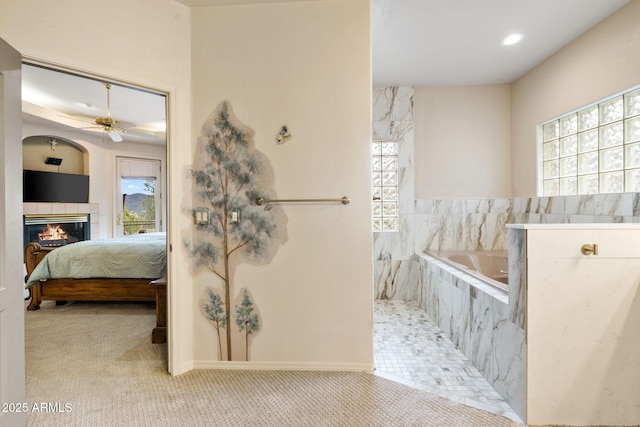 bathroom featuring ensuite bath, recessed lighting, a bath, ceiling fan, and a tile fireplace