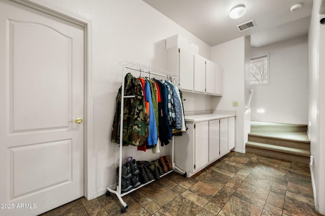 laundry area featuring visible vents, stone finish floor, and baseboards