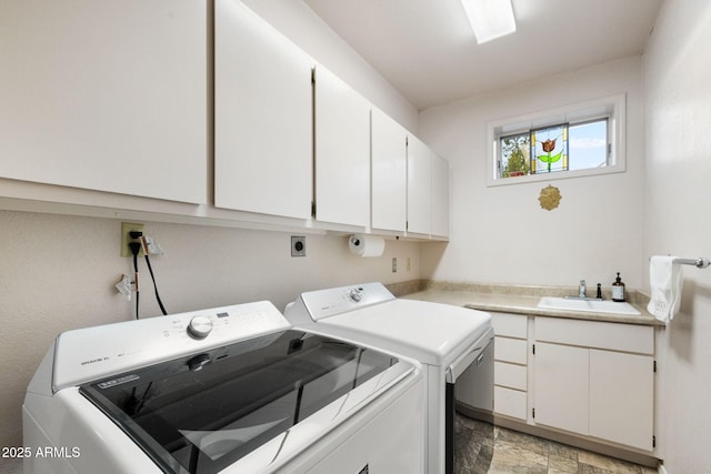 clothes washing area with a sink, stone finish flooring, cabinet space, and washer and clothes dryer