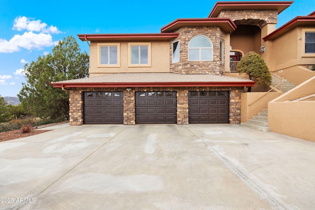 view of front of house featuring concrete driveway, an attached garage, stone siding, and stucco siding