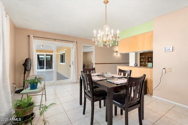 tiled dining room featuring a notable chandelier and a textured ceiling