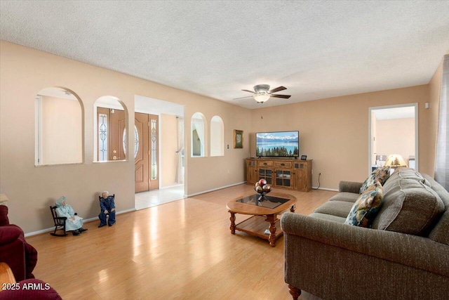 living room with light hardwood / wood-style floors, a textured ceiling, and ceiling fan