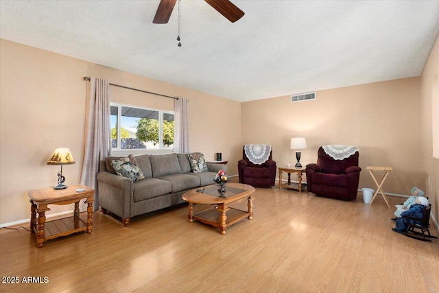 living room featuring light wood-type flooring, a textured ceiling, and ceiling fan