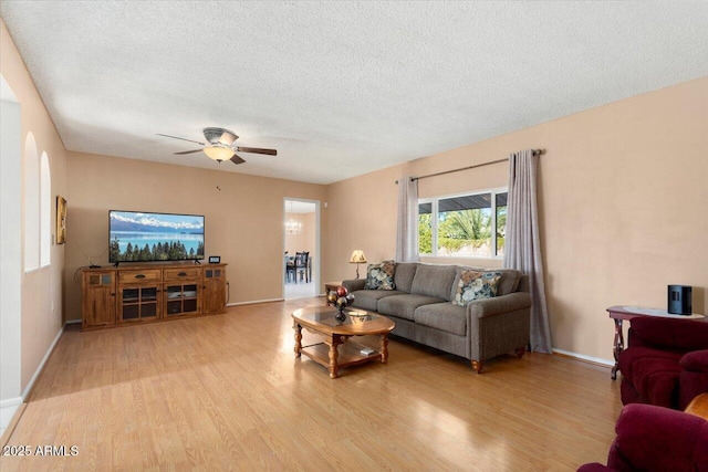 living room featuring light hardwood / wood-style floors, a textured ceiling, and ceiling fan