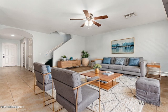 tiled living area featuring arched walkways, visible vents, and ceiling fan