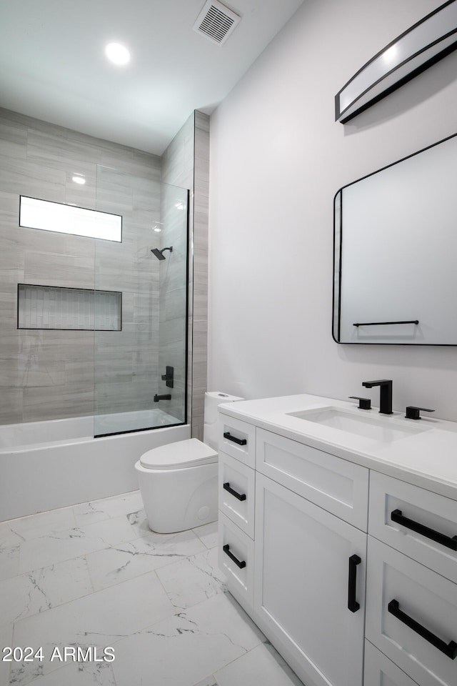 full bathroom with combined bath / shower with glass door, vanity, and toilet