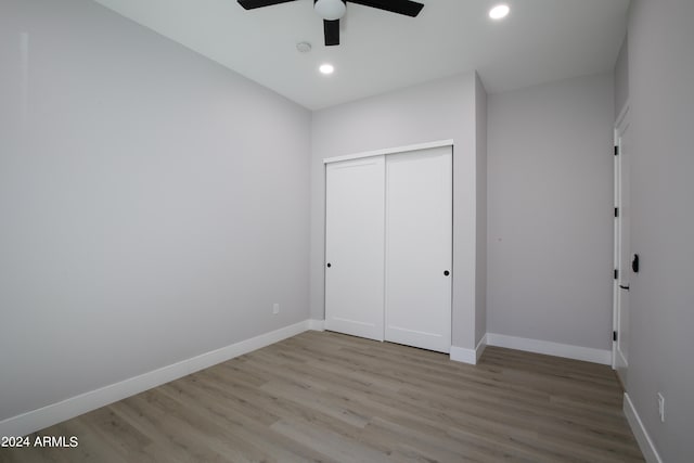 unfurnished bedroom with light hardwood / wood-style floors, ceiling fan, and a closet