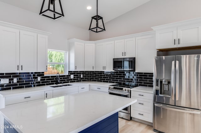 kitchen featuring white cabinetry, stainless steel appliances, lofted ceiling, decorative light fixtures, and sink