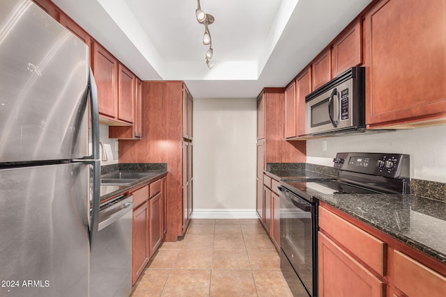 kitchen with light tile patterned floors, rail lighting, a raised ceiling, sink, and stainless steel appliances