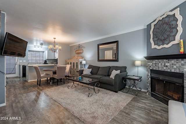 living room featuring a chandelier, wood-type flooring, ornamental molding, and a tile fireplace