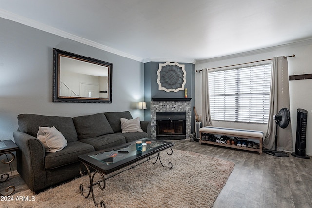 living room with ornamental molding, a tiled fireplace, and wood-type flooring