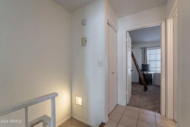 hall featuring a textured ceiling and light colored carpet