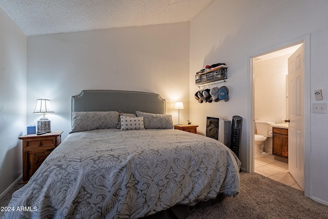 bedroom with connected bathroom, a textured ceiling, and light colored carpet