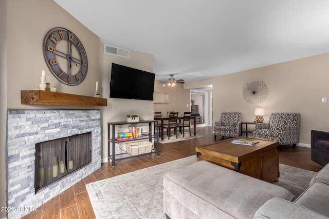 living room with wood-type flooring, ceiling fan, and a fireplace