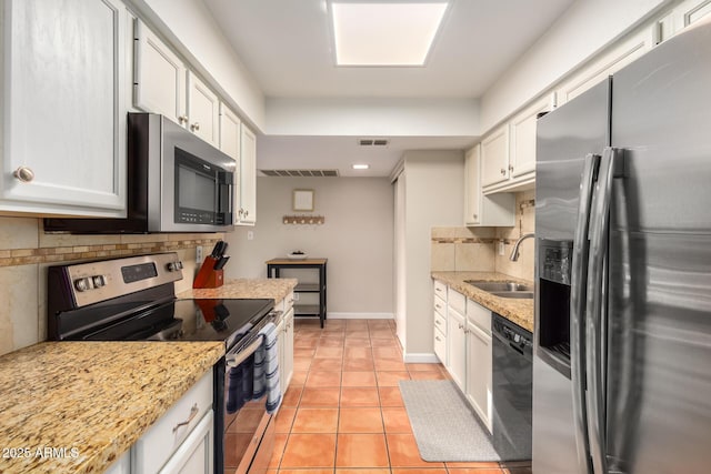 kitchen featuring appliances with stainless steel finishes, tasteful backsplash, sink, white cabinets, and light tile patterned floors