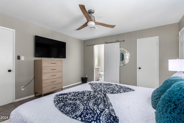 carpeted bedroom with ensuite bath, a barn door, and ceiling fan