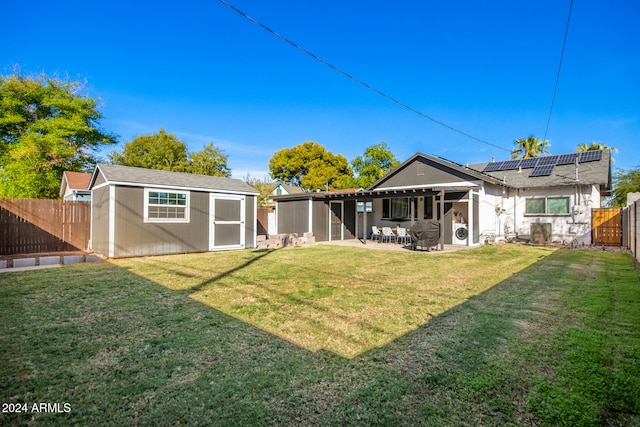 rear view of property featuring a patio area, solar panels, and a yard