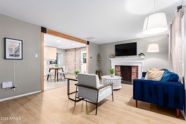 living room featuring light wood-type flooring and a brick fireplace