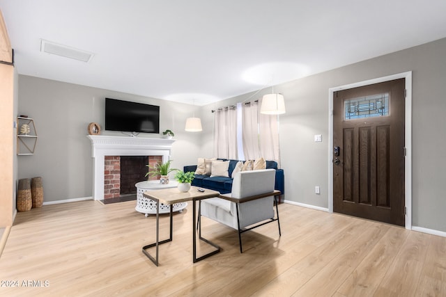 living room featuring light hardwood / wood-style flooring and a brick fireplace