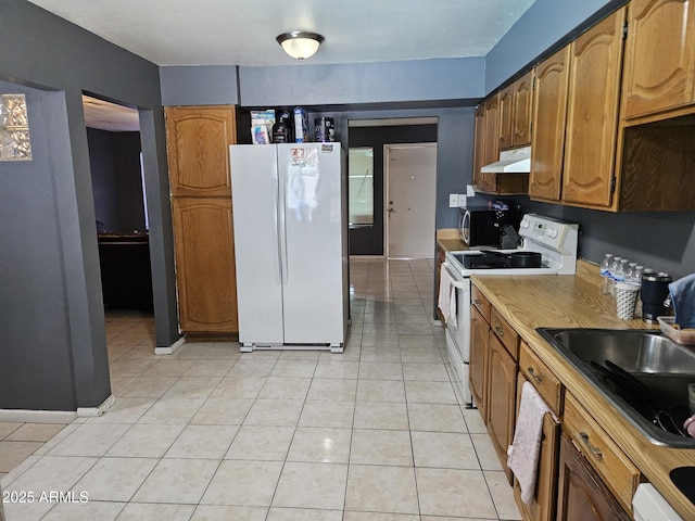 4507 E Saint Catherine Ave, Phoenix, AZ 85042 - kitchen with white appliances, under cabinet range hood, a sink, light tile patterned flooring, and brown cabinetry