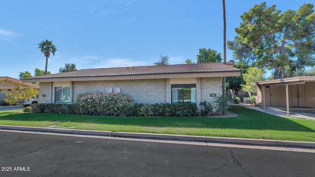 view of front facade with brick siding, a front yard, and a carport