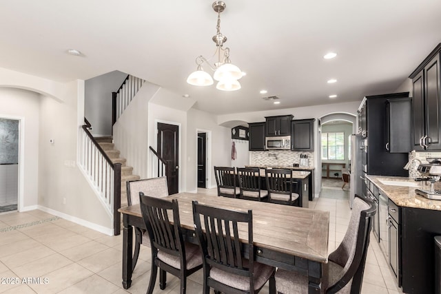 20709 W Delaney Dr, Buckeye, AZ 85396 - dining space featuring arched walkways, light tile patterned floors, a chandelier, recessed lighting, and stairway